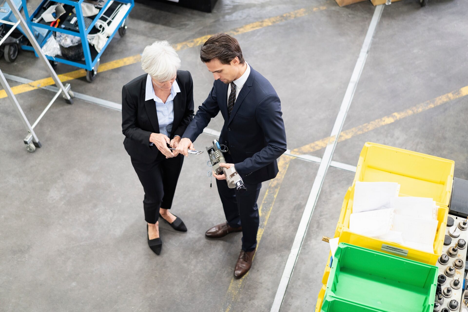 Businessman and senior businesswoman examining workpiece in a factory